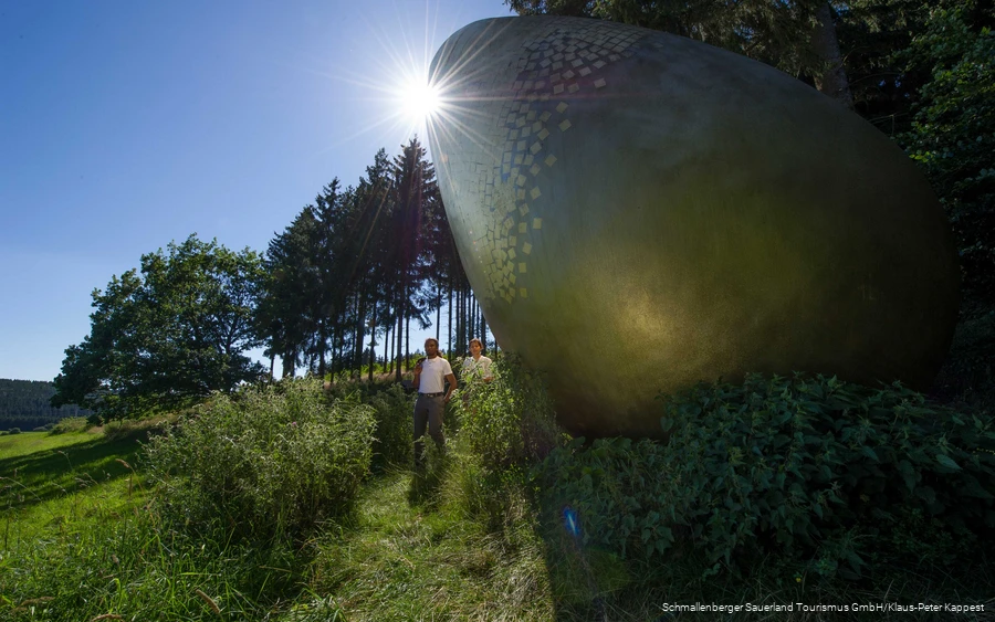 Two hikers at the "golden egg" on the Forest Sculpture Trail.