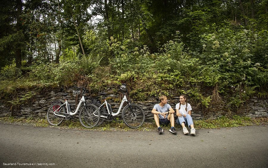sabrinity_tourenrad084_fullwidth.jpg Radfahrerpärchen macht eine Pause am Wegesrand.