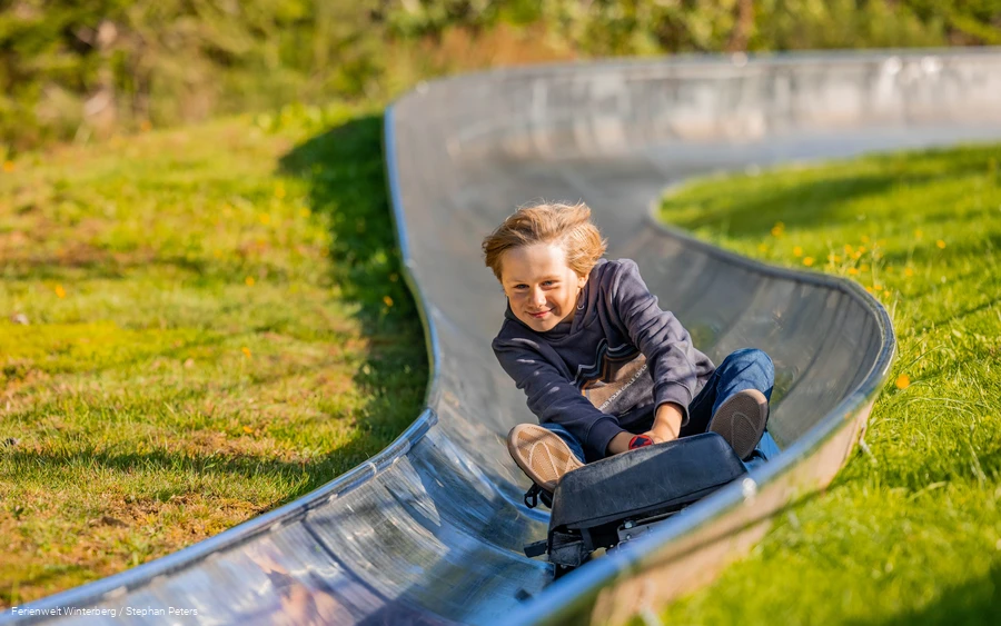 Ein Kind fährt die Sommerrodelbahn hinab.