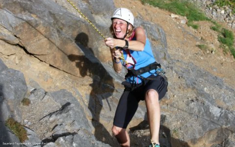 Frau klettert am Felsen.