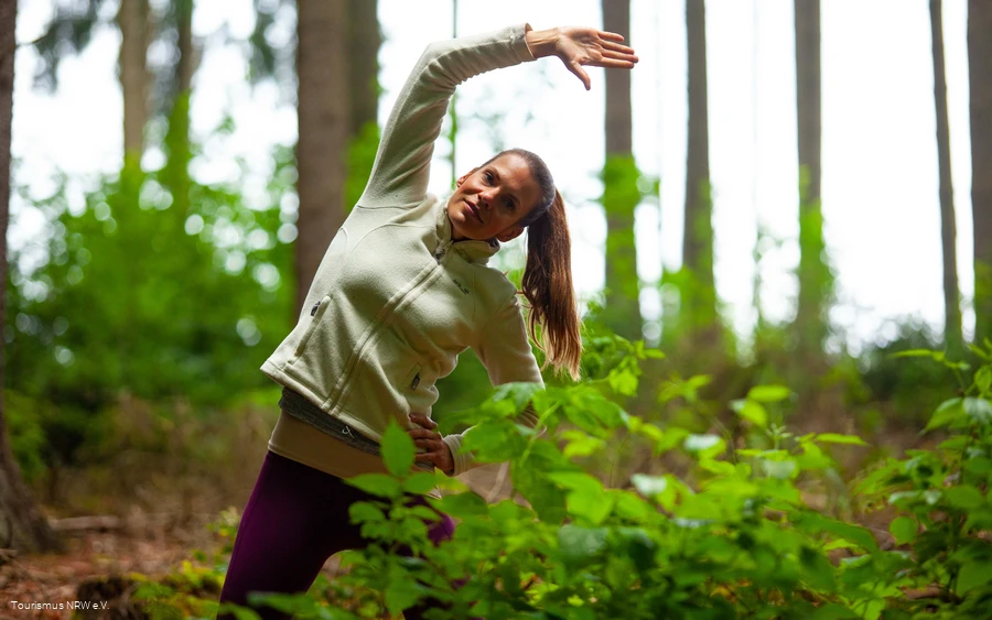 Een vrouw doet een oefening in het bos