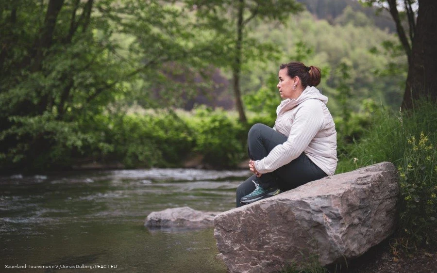 Eine Frau schaut in das plätschernde Wasser an einem Kneipptretbecken