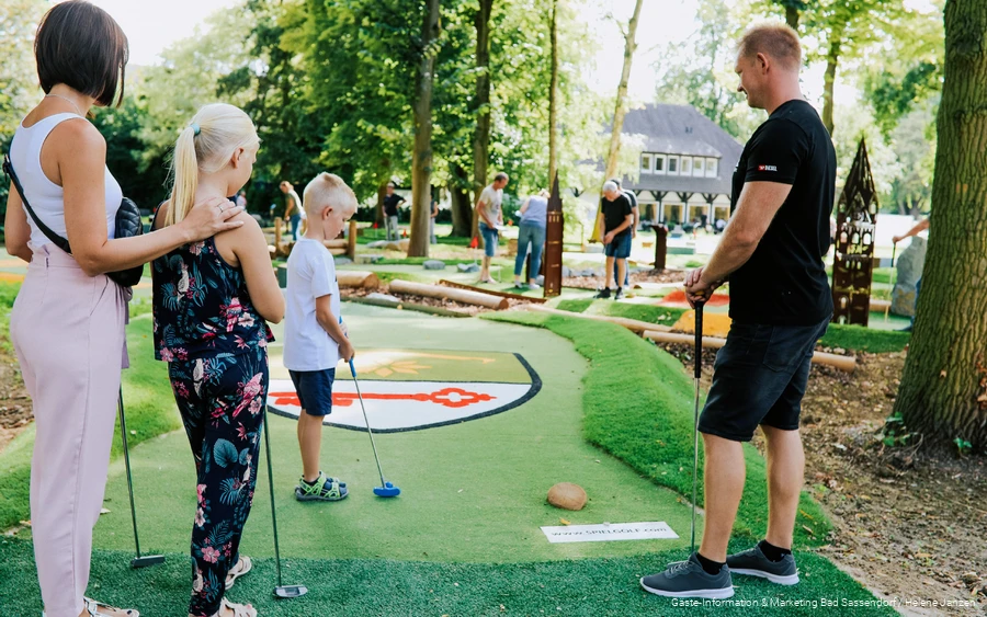Eltern und die ältere Schwester schauen dem Sohn beim Abschlag auf dem Adventure Golf Platz in Bad Sassendorf zu. Er ist gut besucht.