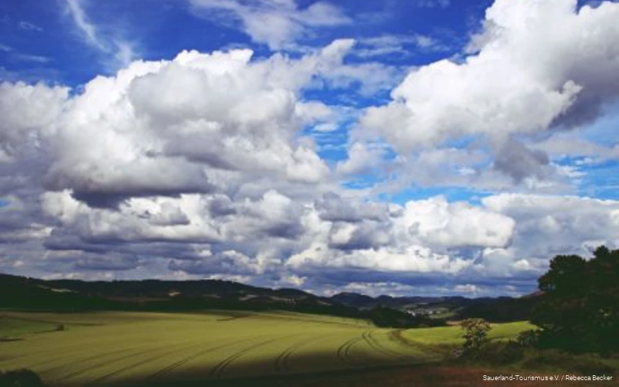 Dicke Wolken am blauen Himmel ziehen über die Sauerländer Landschaft.