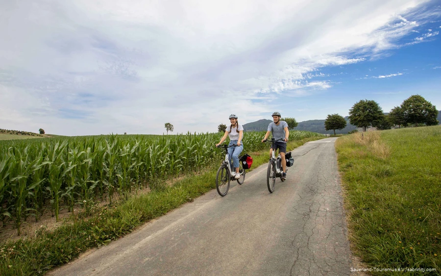 Een stel fietst rustig over een fietspad door groene weiden.