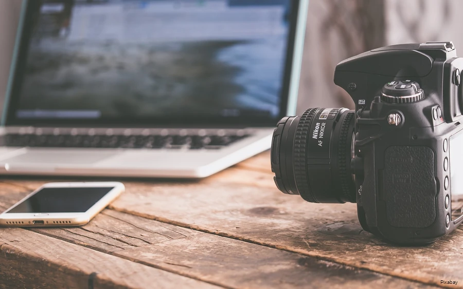View of a table with laptop, smartphone and SLR camera.