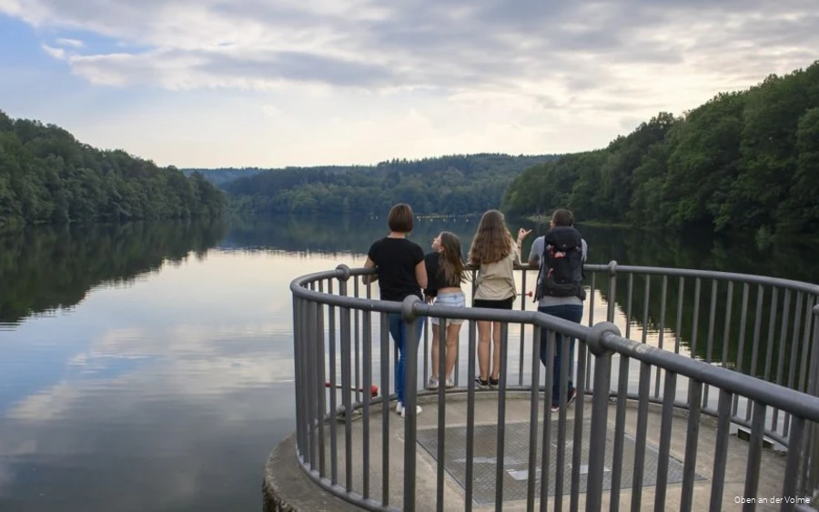 A family stands on a viewing platform and looks out over the Glörtalsperre dam.