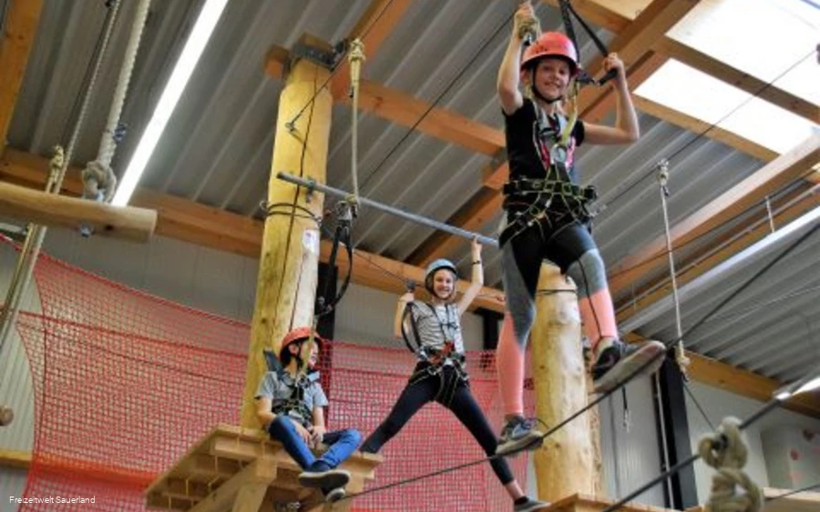 Kinderen klimmen in het indoor hoge touwenparcours.