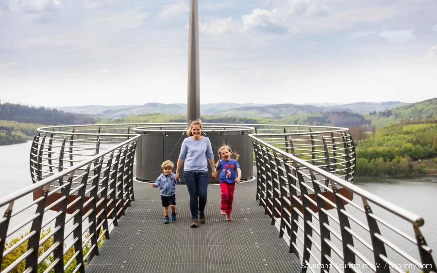 Eine Mutter läuft mit zwei Kindern an der Hand über den Skywalk Biggeblick.