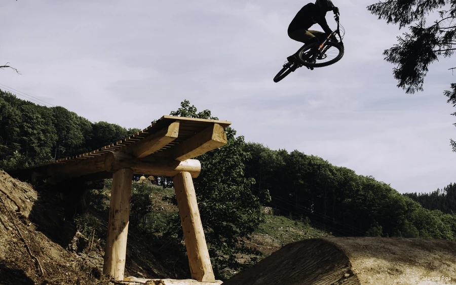 Ein Downhill-Fahrer bei einem Sprung in der Luft, nachdem er über ein Hindernis gefahren ist