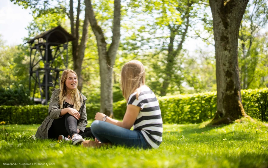 Two friends are sitting on the grass and chatting.