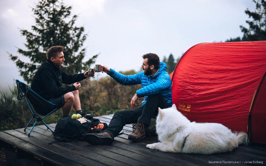 Hund mit zwei Wanderern auf einem Trekkingplatz