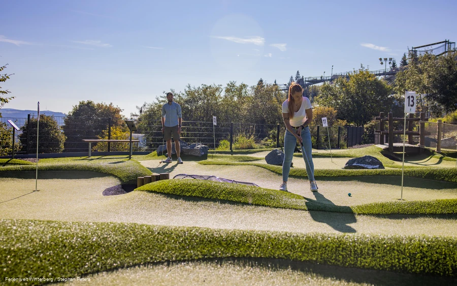 Zwei Personen beim Minigolf spielen.