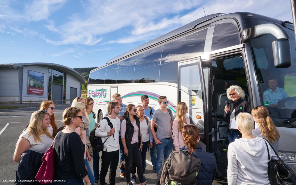 Eine junge Reisegruppe vor dem Reisebus.