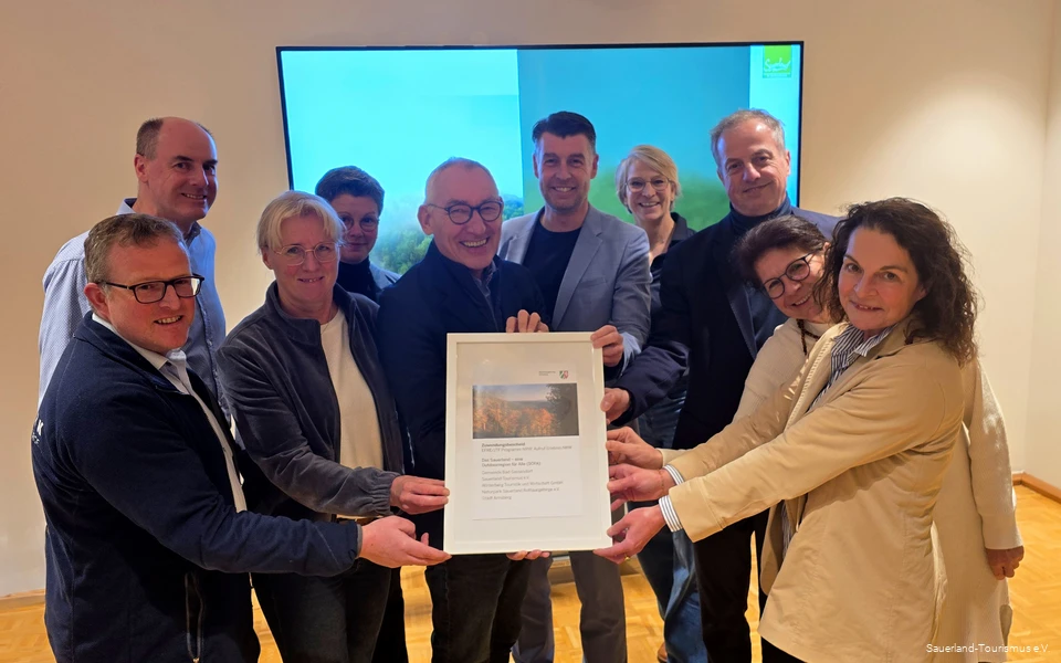 Die zehn Projektbeteiligten halten glücklich den Förderbescheid für das Barrierefreiheits-Projekt in den Händen.