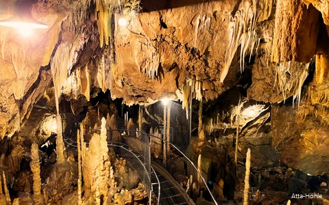 Einblick in die Atta-Höhle mit Stalaktiten und Stalakmiten und einem Gang, der zwischen ihnen durchführt.