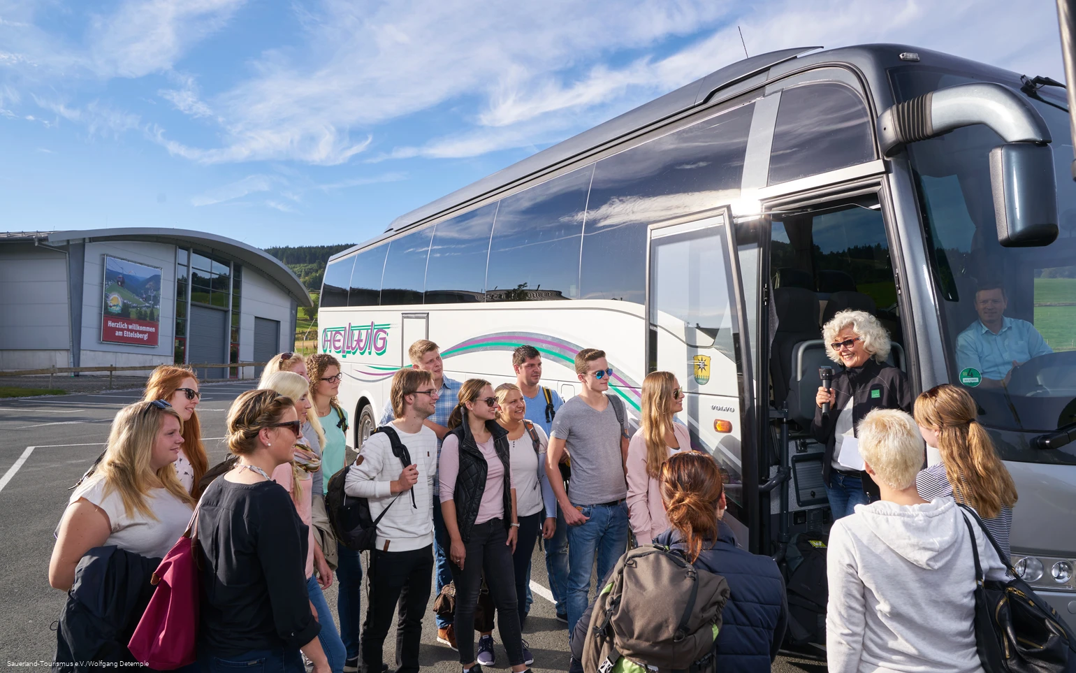 Eine junge Reisegruppe vor dem Reisebus.