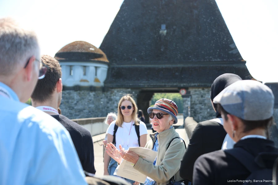 Einblick in eine Gruppenführung auf der Staumauer des Möhnesees. Eine ältere Frau steht als Guide in der Mitte der Gruppe.