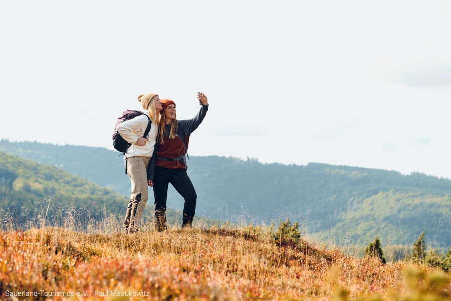Twee vrouwen nemen een selfie voor een prachtige bosrijke achtergrond