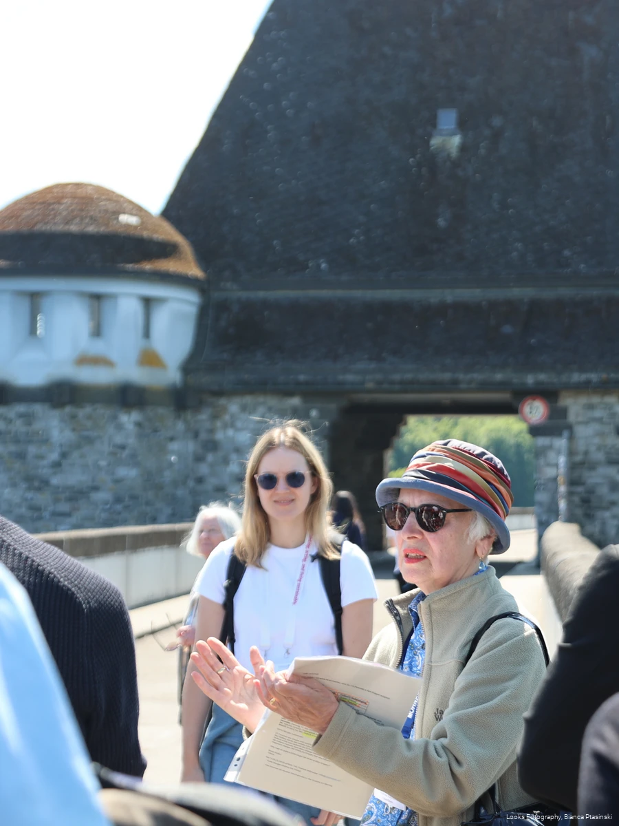 Einblick in eine Gruppenführung auf der Staumauer des Möhnesees. Eine ältere Frau steht als Guide in der Mitte der Gruppe.