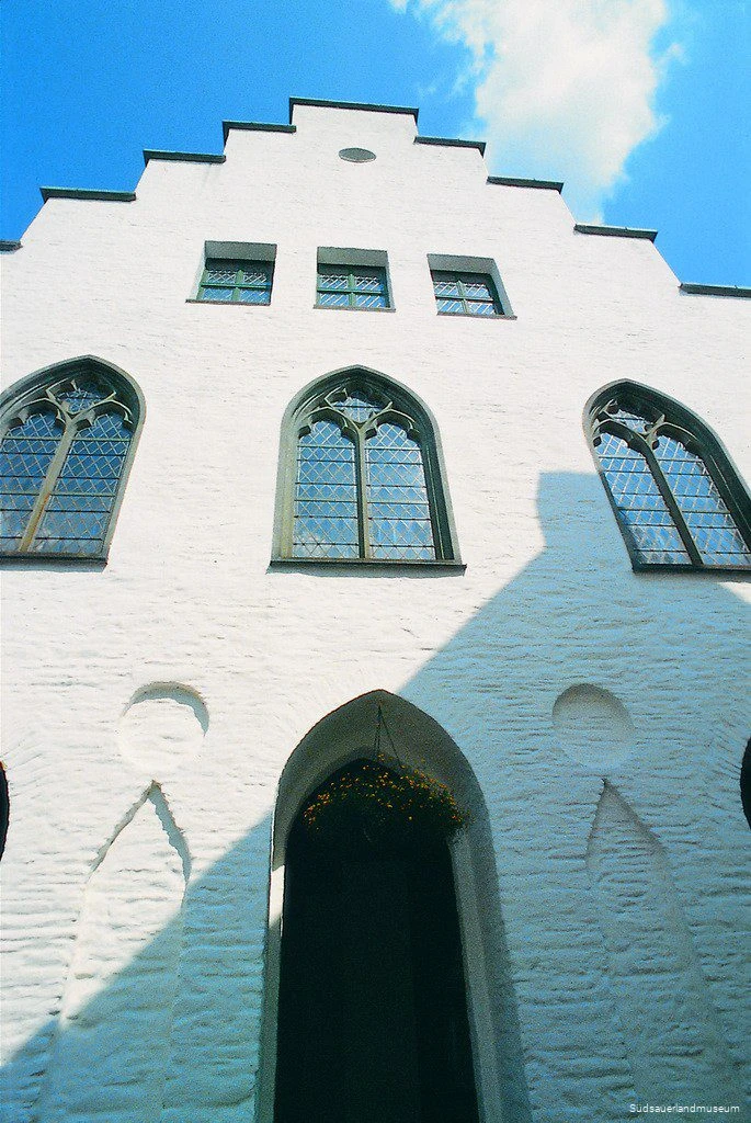 Nahaufnahme der weißen Fassade des Südsauerlandmuseums mit einem Kranz über einer Tür.
