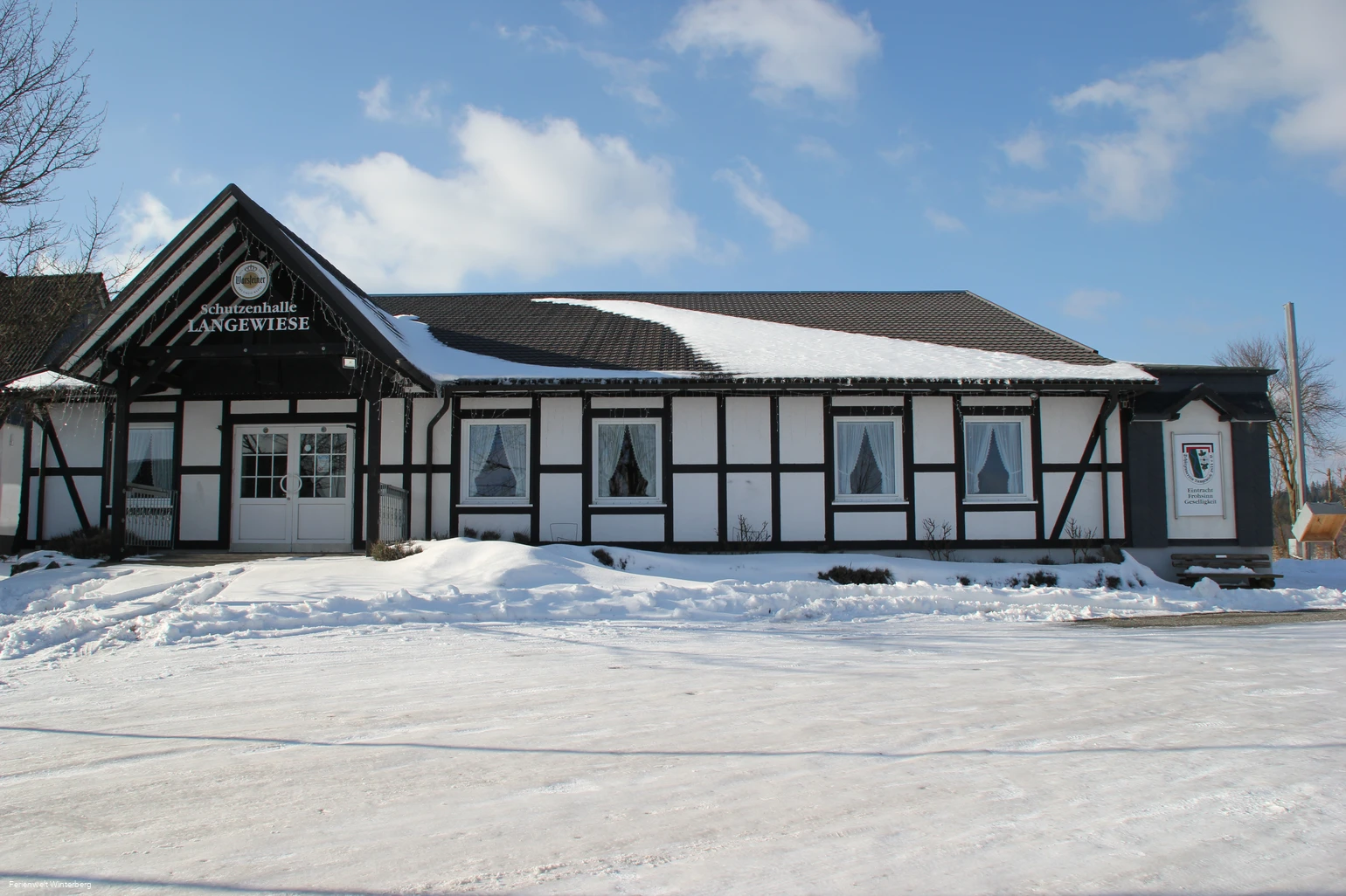 Die Schützenhalle Langewiese mit dem sich davor befindlichen zugeschneiten Parkplatz im Winter.