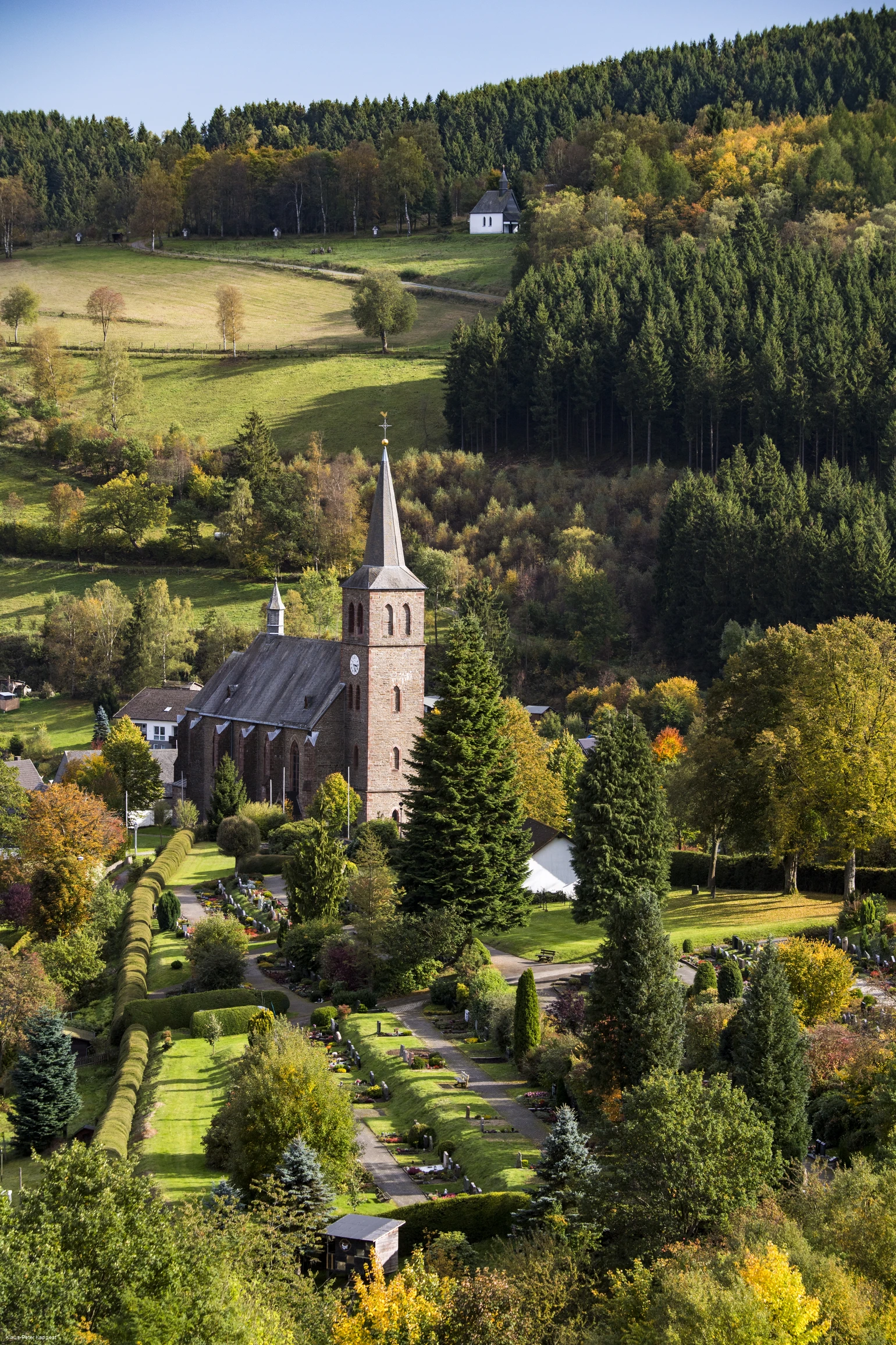 Drohnenaufnahmeeiner Kirche umgeben von Wiesen und Wäldern.