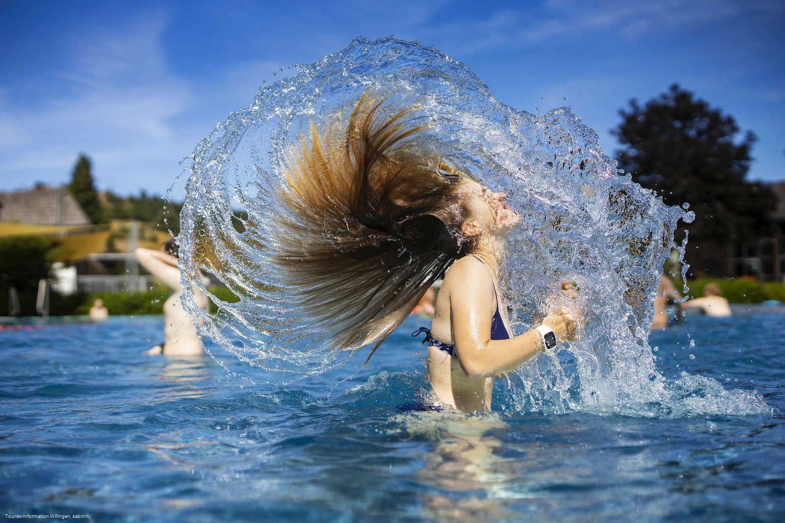 Mädchen schüttelt Wasser aus den Haaren im Freibad Usseln