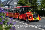 Eine rot-gelbe Eisenbahn fährt die Straße entlang.