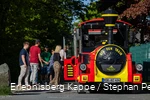 Einige Personen steigen in eine rot-gelbe Eisenbahn ein.