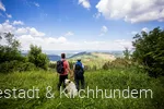 Hund mit Wanderern vor einer tollen Aussicht