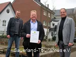 Drei Männer lächeln, der Mittlere hält die Mitgliedurkunde des Sauerland-Tourismus