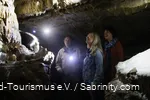 Zwei Frauen und der Höhlenführer bestaunen die Höhle.