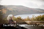 Een vrouw ontspant terwijl ze leest in het herfstlandschap rond de Biggesee.