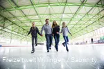 Vader, moeder en twee dochters schaatsen hand in hand.