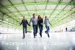 Father, mother and two daughters skate hand-in-hand.