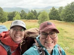 Anne Abendroth und ihre Freundin grinsen auf einer ihrer Wanderungen in die Kamera. Sie tragen Outdoorkleidung, Kappen und Wanderrucksäcke.
