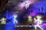 Die Dechenhöhle ist mit bunten Lichtern ausgeleuchtet und beleuchtete Strichmännchen stehen an verschiedenen Ecken.