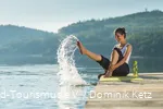 Eine Frau sitzt auf einem Steg am Hennesee und spritzt mit Wasser.