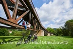Paar zittend op de ligger van een brug met twee e-bikes onder hen