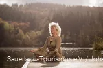 Een vrouw ontspant met yoga-oefeningen bij een meer.