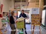 Ein Mitarbeiter des Sauerland-Tourismus berät eine Besucherin der Fahrradmesse in Essen an seinem Stand. Er hält ihr eine Karte des Sauerlands hin.