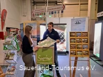 Ein Mitarbeiter des Sauerland-Tourismus berät eine Besucherin der Fahrradmesse in Essen an seinem Stand. Er hält ihr eine Karte des Sauerlands hin.
