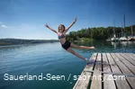 Ein Mädchen springt vom Steg in den See.
