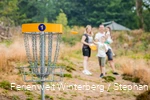 Eine Familie mit zwei Kindern beim Disc-Golf spielen.