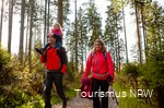 A family on a hike through the autumnal Sauerland landscape. The father carries his daughter on his shoulders.