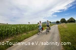 Een stel fietst rustig over een fietspad door groene weiden.