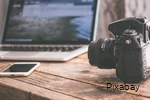 View of a table with laptop, smartphone and SLR camera.