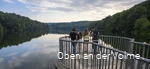 A family stands on a viewing platform and looks out over the Glörtalsperre dam.