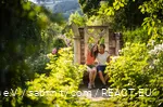 Mother and daughter sit in a blooming garden and take a selfie.